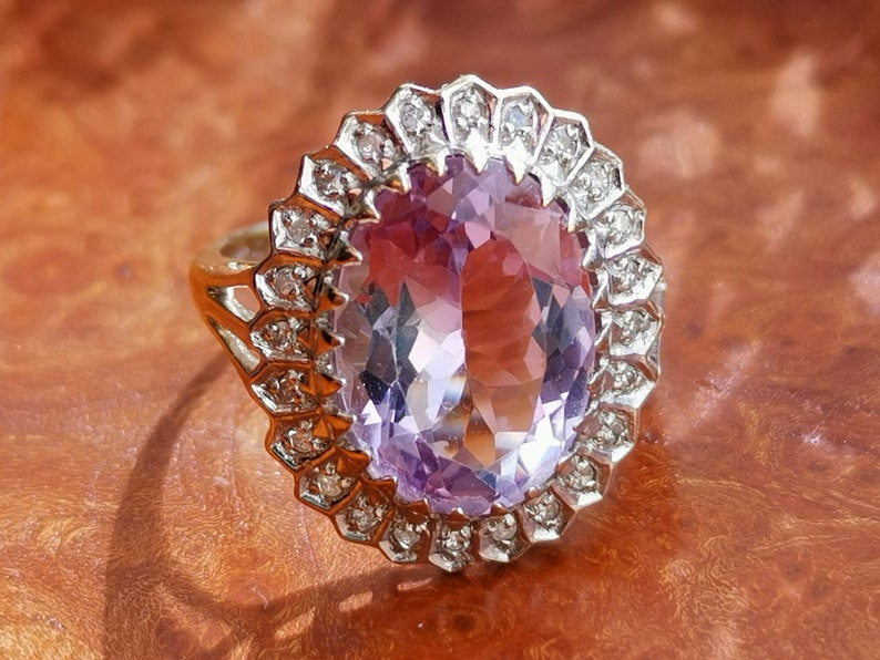 Op de afbeelding: Een ring met een grote ovale amethist-edelsteen, omringd door een halo van kleinere diamanten.