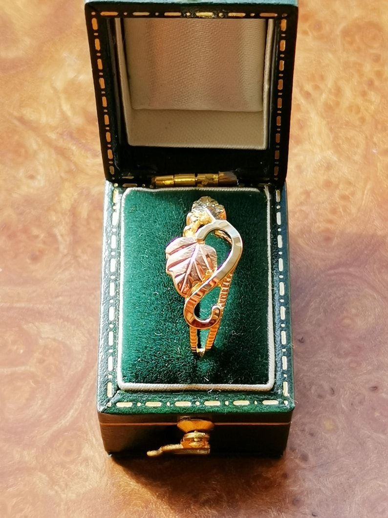 May include: A gold and green leaf ring in a green velvet ring box.