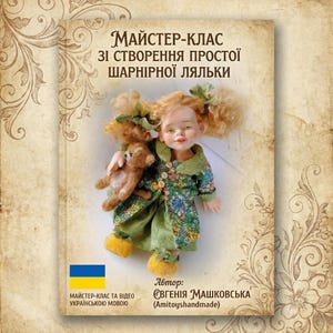 Peut inclure: Une poupée aux cheveux blonds bouclés, vêtue d'une robe verte à motifs floraux, tenant un petit ours en peluche. La poupée est présentée sur une couverture de livre avec du texte ukrainien et un drapeau ukrainien. Le titre du livre est "Master Class on Creating a Simple Jointed Doll."
