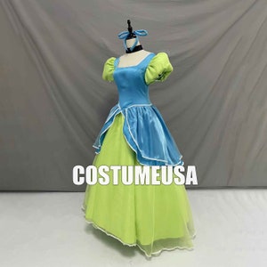 May include: A light blue and lime green princess dress with a white trim. The dress has a puffed sleeve and a full skirt. The dress is on a mannequin with a blue bow on its head. The text "CostumeUSA" is printed on the skirt.