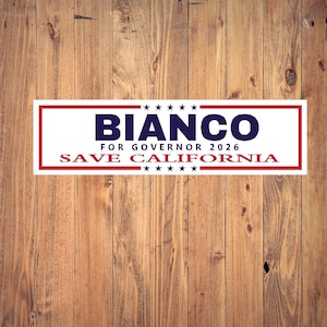 May include: A rectangular bumper sticker with a white background and red border. The text "BIANCO" in navy blue is above "FOR GOVERNOR 2026 SAVE CALIFORNIA" in red. Five white stars are above and below the text. The background is a wooden surface.