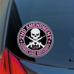 May include: A black and white sticker with a skull and crossbones, two rifles, and the text "2nd Amendment" in a pink circle. The text "America's Original Homeland Security" is also in the circle, with the year "1789" in the center.