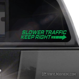 May include: Green vinyl decal with the text "Slower Traffic Keep Right" and a right arrow. The decal is on a black car window.