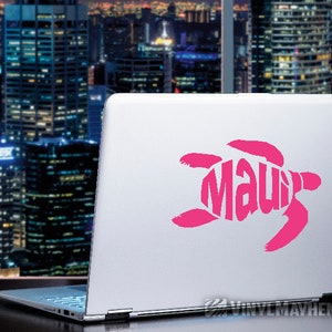 May include: A laptop with a bright pink turtle design that spells out "Maui". The design is a stylized turtle shape with the word "Maui" incorporated into the design. The laptop is open, and the background shows a cityscape.