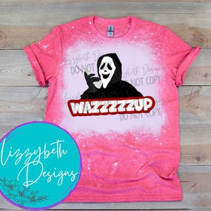 Op de afbeelding: Een roze T-shirt met een wit bleekontwerp van een geest die een masker draagt, een telefoon vasthoudt en de tekst "WAZZZZZZUP" heeft.