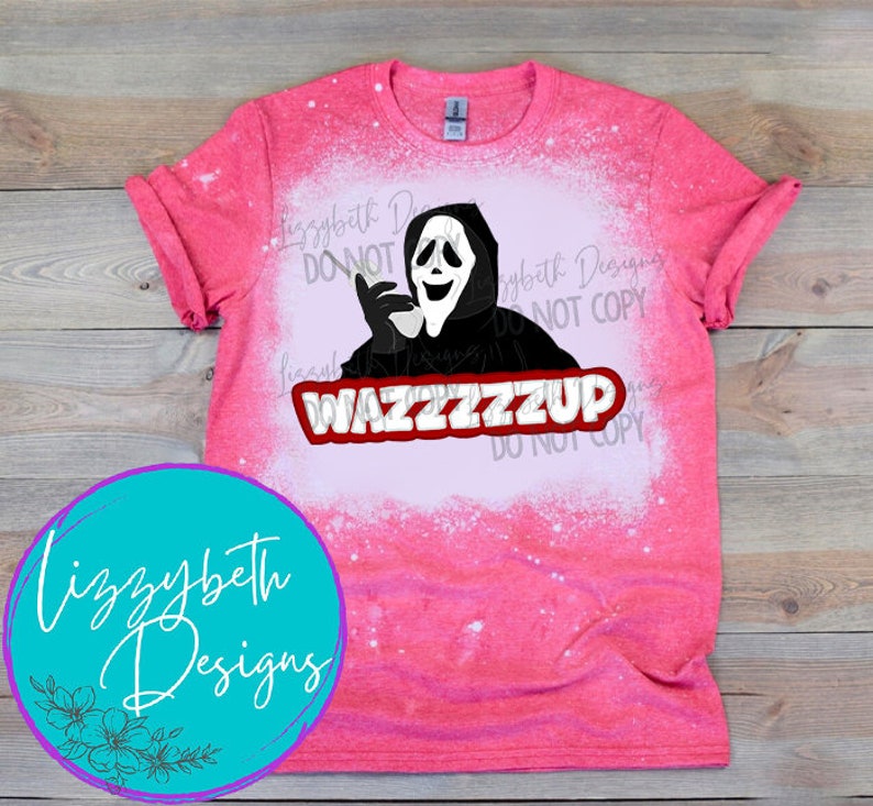 Op de afbeelding: Een roze T-shirt met een wit bleekontwerp van een geest die een masker draagt, een telefoon vasthoudt en de tekst "WAZZZZZZUP" heeft.