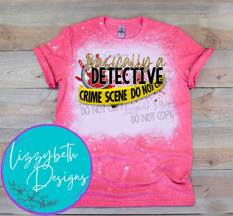 May include: Pink bleached t-shirt with a graphic design that says "Basically a Detective" with a yellow crime scene tape that says "Crime Scene Do Not Cross".
