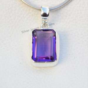 May include: A silver pendant with a large, rectangular, purple amethyst gemstone. The pendant is on a silver chain.