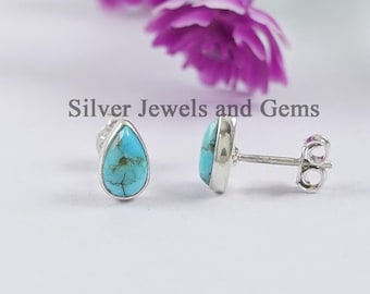 Op de afbeelding: Een paar zilveren druppelvormige oorbellen met turquoise stenen. De oorbellen hebben een oorbelsteker met vlinder achterkant.