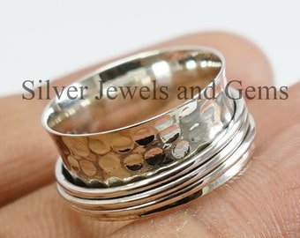 May include: A silver-colored spinner ring with a textured band and multiple smooth bands. The ring has the text "Silver Jewels and Gems".