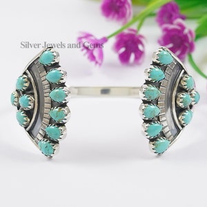May include: A silver cuff bracelet with turquoise stones set in a geometric pattern. The bracelet is open on both ends and has a curved shape.