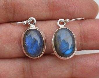 May include: A pair of silver dangle earrings with oval-shaped blue labradorite gemstones.