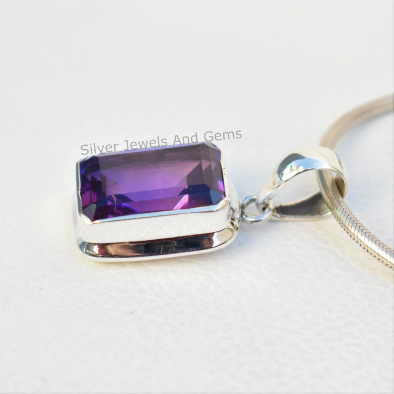 May include: A silver pendant featuring a large, rectangular, purple amethyst gemstone. The pendant is on a silver chain.