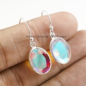 Puede incluir: Un par de pendientes de plata con piedras preciosas iridiscentes de forma ovalada. Las piedras preciosas presentan un efecto arco&iacute;ris con tonos de azul, verde y rosa.