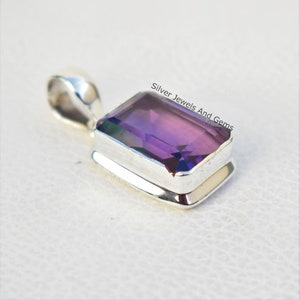May include: A silver pendant featuring a purple amethyst gemstone. The gemstone is cut in a rectangular shape and has a faceted finish. The pendant is set in a silver bezel setting.