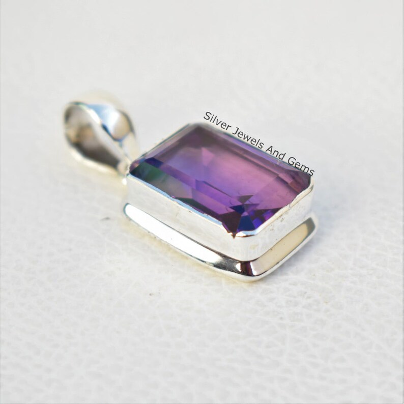 May include: A silver pendant featuring a purple amethyst gemstone. The gemstone is cut in a rectangular shape and has a faceted finish. The pendant is set in a silver bezel setting.