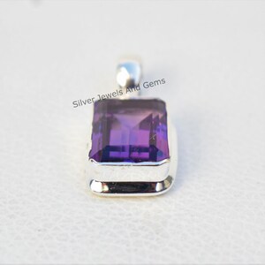 May include: A silver pendant featuring a large, rectangular, purple amethyst gemstone. The gemstone is set in a silver bezel with a smooth, polished finish. The pendant is a simple and elegant design.