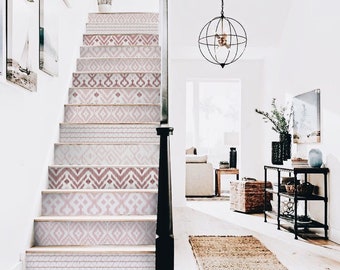 May include: A white staircase with pink and white patterned stair treads. The staircase is in a white hallway with a rug on the floor and a black globe chandelier hanging from the ceiling.