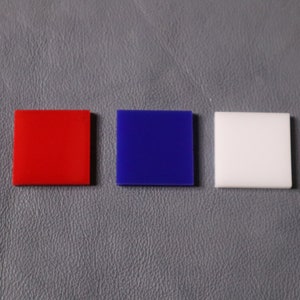 May include: Three square tiles, one red, one blue, and one white.