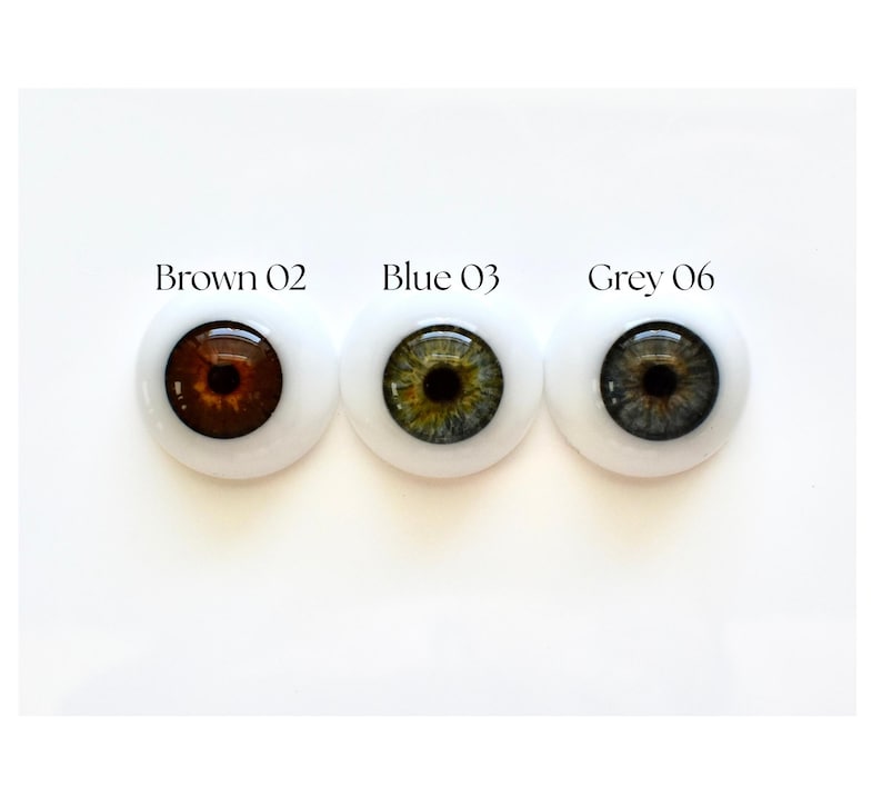 K&ouml;nnte beinhalten: Drei Puppenaugen in Braun, Blau und Grau, jeweils mit wei&szlig;em Hintergrund. Das braune Auge ist mit "Brown 02" beschriftet, das blaue Auge mit "Blue 03" und das graue Auge mit "Grey 06".
