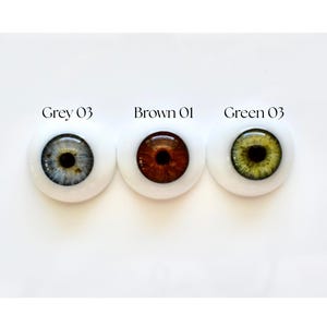 K&ouml;nnte beinhalten: Drei Puppenaugen nebeneinander, jeweils mit wei&szlig;em Hintergrund. Die Augen sind grau, braun und gr&uuml;n. &Uuml;ber jedem Auge steht "Grey 03", "Brown 01" und "Green 03".