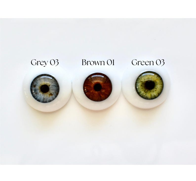 K&ouml;nnte beinhalten: Drei Puppenaugen nebeneinander, jeweils mit wei&szlig;em Hintergrund. Die Augen sind grau, braun und gr&uuml;n. &Uuml;ber jedem Auge steht "Grey 03", "Brown 01" und "Green 03".