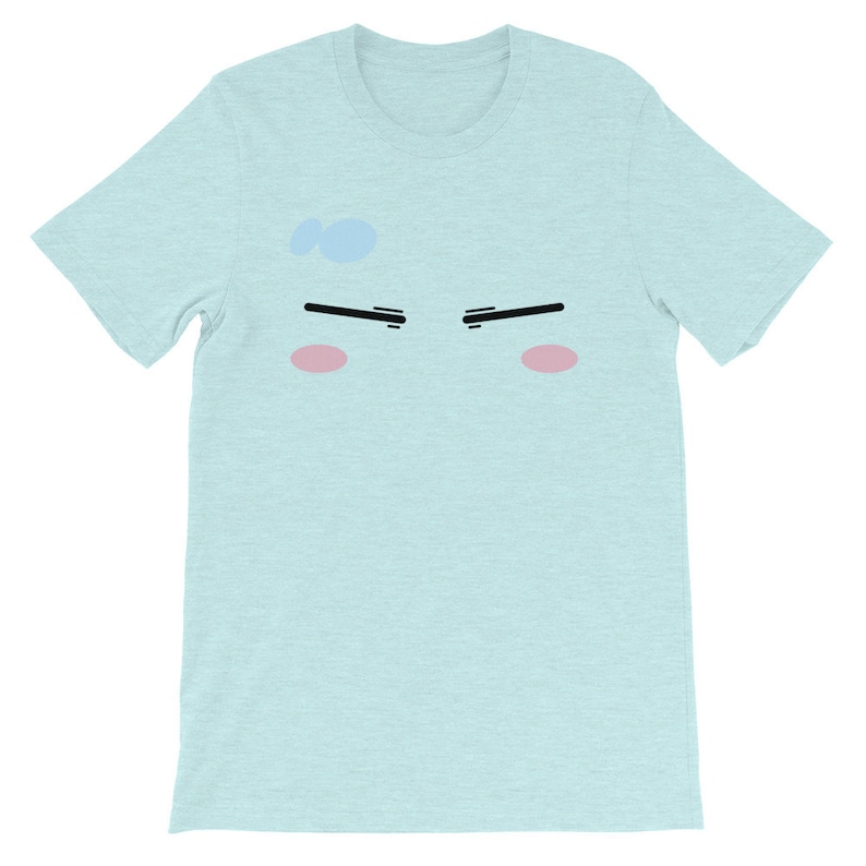 May include: A light blue t-shirt with a cartoon face printed on the front. The face has black eyebrows, black eyes, and pink cheeks.