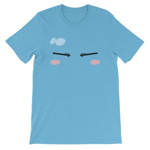 May include: A light blue t-shirt with a cartoon face printed on the front. The face has black eyebrows, pink cheeks, and a light blue sweat drop on the forehead.