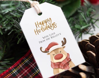 Può includere: Etichetta regalo bianca con scritta dorata glitterata che dice "Happy Holidays" e "With Love From The Kelley's". Un renna di cartone animato con un cappello di Babbo Natale rosso e una sciarpa rossa e bianca è illustrata sull'etichetta.