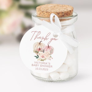 May include: A round white thank you tag with pink lettering. The tag features a watercolour illustration of two white pumpkins with pink accents and pink flowers. The text on the tag reads "Thank you" and "Victoria's Baby Shower 10.23.2023".