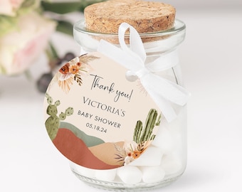 May include: A round, beige thank you tag with a cactus and desert landscape design. The tag says "Thank you! Victoria's Baby Shower 05.18.24".