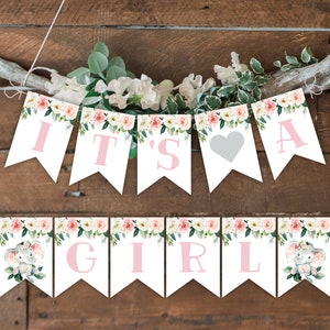 Op de afbeelding: Een baby shower banner met roze bloemen- en olifantendesigns. De banner luidt "It's a Girl" met een hart tussen de woorden "a" en "girl".