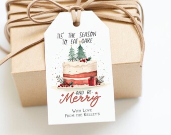May include: White gift tag with a red and white cake illustration, two green Christmas trees, and red berries. The text reads "Tis' the season to eat cake and be merry" with "With love, from the Kelley's" at the bottom.