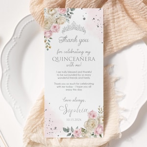 May include: A rectangular Quinceañera thank you card with floral and tiara accents. The card features text that reads "Thank you for celebrating my Quinceañera with me!" and is decorated with pink and white roses and greenery.