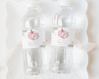 Puede incluir: Dos botellas de agua de plástico transparente con etiquetas rosas y blancas. Las etiquetas presentan una ilustración de acuarela de una calabaza rosa con detalles florales. El texto en las etiquetas dice "Victoria's Baby Shower 10.14.23".