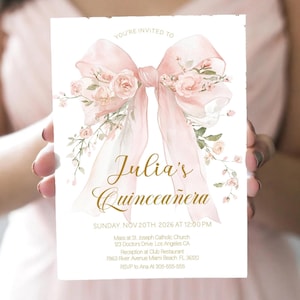May include: A Quinceañera invitation card. The card features a watercolour design of a pink bow with floral accents and the text "Julia's Quinceañera". Additional details include the date, time, and location, held by a person.