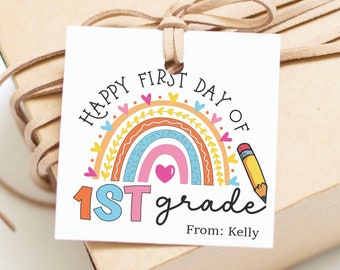Könnte beinhalten: Ein weißer Geschenkanhänger mit einem Regenbogen, Herzen und einem Bleistift. Der Text lautet "Happy First Day of 1st grade" und "From: Kelly".