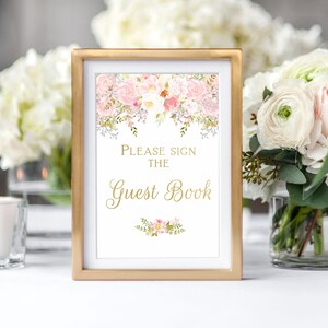 May include: A gold framed sign with a floral design and the text "Please sign the Guest Book".