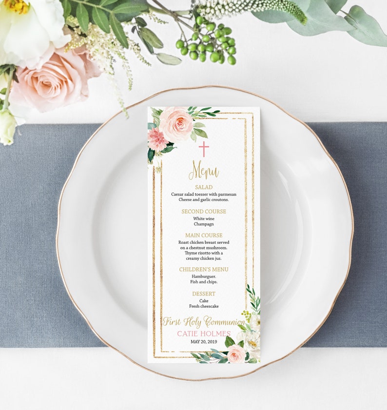 May include: A gold and white menu card with floral designs and a gold cross. The menu includes a salad, second course, main course, children's menu, and dessert. The text reads "Menu", "First Holy Communion", "Catie Holmes", and "May 20, 2019".