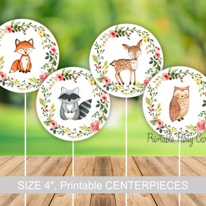 May include: Four 4-inch printable centerpieces featuring woodland animals. Each centerpiece has a white background with a wreath of green leaves and pink flowers. The animals are a fox, a deer, a raccoon, and an owl.