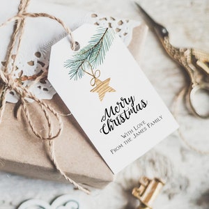 May include: A white gift tag with a watercolor illustration of a pine branch with a gold star ornament. The tag reads "Merry Christmas" with the text "With Love From The James Family" below.
