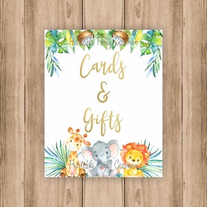 K&ouml;nnte beinhalten: Ein wei&szlig;es Schild mit goldener Schrift, auf dem "Cards & Gifts" steht. Das Schild ist mit gr&uuml;nen Bl&auml;ttern, Kokosn&uuml;ssen und einer Giraffe, einem Elefanten und einem L&ouml;wen verziert.