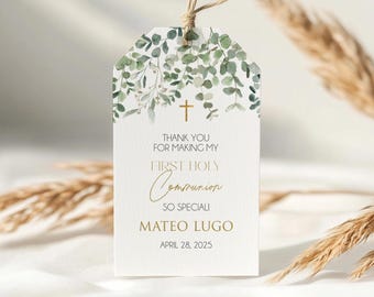 Puede incluir: Una etiqueta de regalo blanca con un diseño de acuarela de hojas verdes y una cruz dorada. La etiqueta dice "Gracias por hacer que mi Primera Comunión sea tan especial, Mateo Lugo, 28 de abril de 2025."