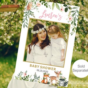 May include: A printable photo booth prop for a baby shower. The prop features a floral frame with a space for a photo, the text "Lauren's Baby Shower 06.20.2020", and a woodland animal theme with a fox, deer, and raccoon.