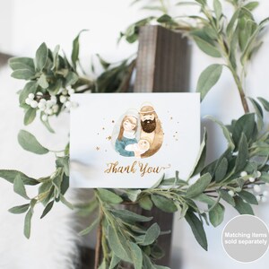Pu&ograve; includere: Un'illustrazione ad acquerello della Sacra Famiglia con una scritta "Grazie" in oro. L'immagine &egrave; su una carta bianca con uno sfondo di stelle dorate.