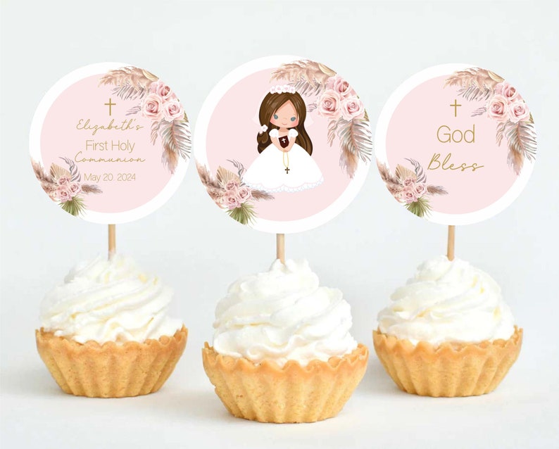 May include: Three pink and white cupcake toppers with a gold cross, floral design, and a girl in a white dress. The text on the toppers reads "Elizabeth's First Holy Communion May 20, 2024" and "God Bless".