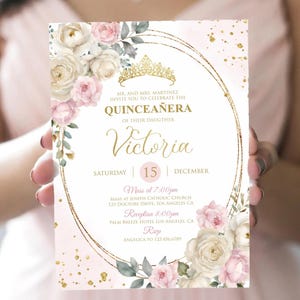 May include: A Quincea&ntilde;era invitation card with a gold frame, floral accents, and the name "Victoria." The card features a tiara illustration, the date, and event details. The color scheme includes pink, white, and gold.