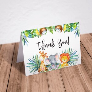Może przedstawiać: Kartka z podziękowaniem z akwarelową ilustracją żyrafy, słonia i lwa otoczonych zielonymi liśćmi i kokosami. Tekst "Thank You!" jest napisany czarnym kolorem.