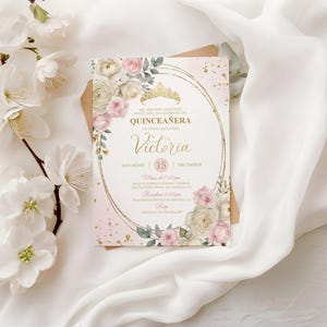 May include: A Quincea&ntilde;era invitation card with a gold frame, a crown, and floral accents. The invitation is pink and gold with the name "Victoria" in elegant script. The date is December 15th.