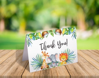 May include: Thank you card with a jungle theme. The card features a giraffe, elephant, and lion with green leaves and coconuts.